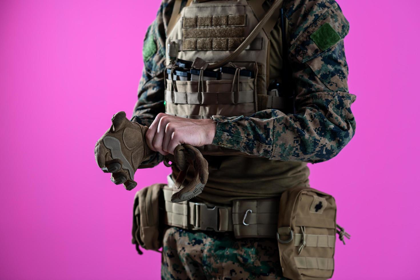 Nahaufnahme von Soldatenhänden, die schützende Kampfhandschuhe auf rosa Hintergrund legen foto