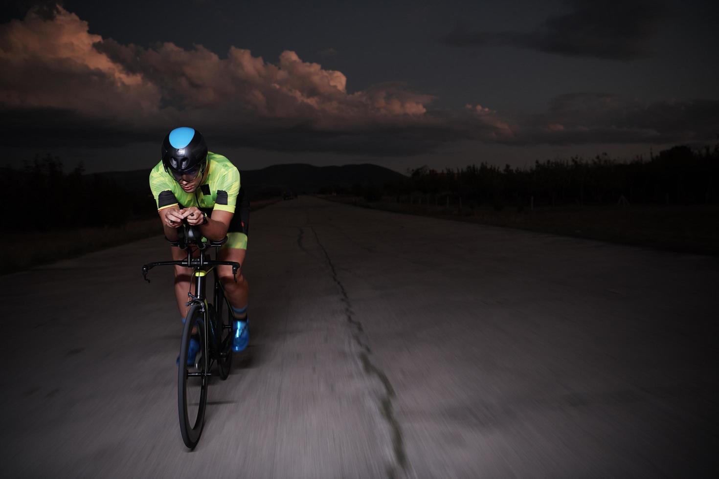 Triathlonsportler, der nachts schnell Fahrrad fährt foto