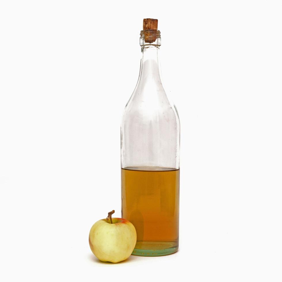 hohe Flasche mit Apfelessig und einem Apfel isoliert auf weißem Hintergrund. foto