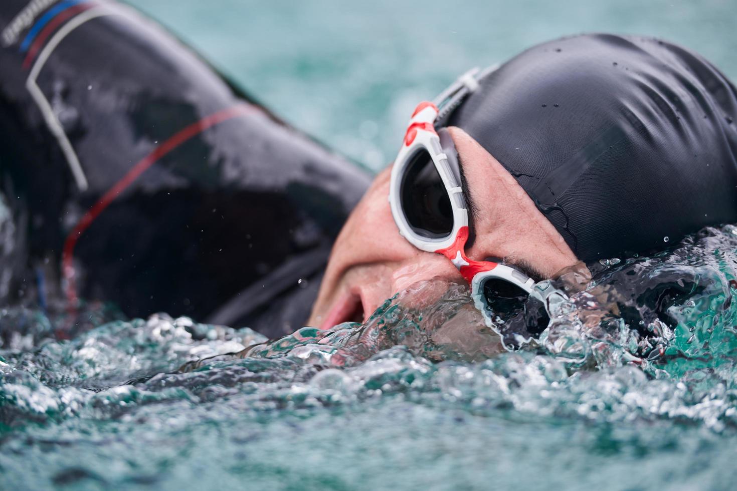 Triathlon-Athlet, der auf dem See schwimmt und einen Neoprenanzug trägt foto