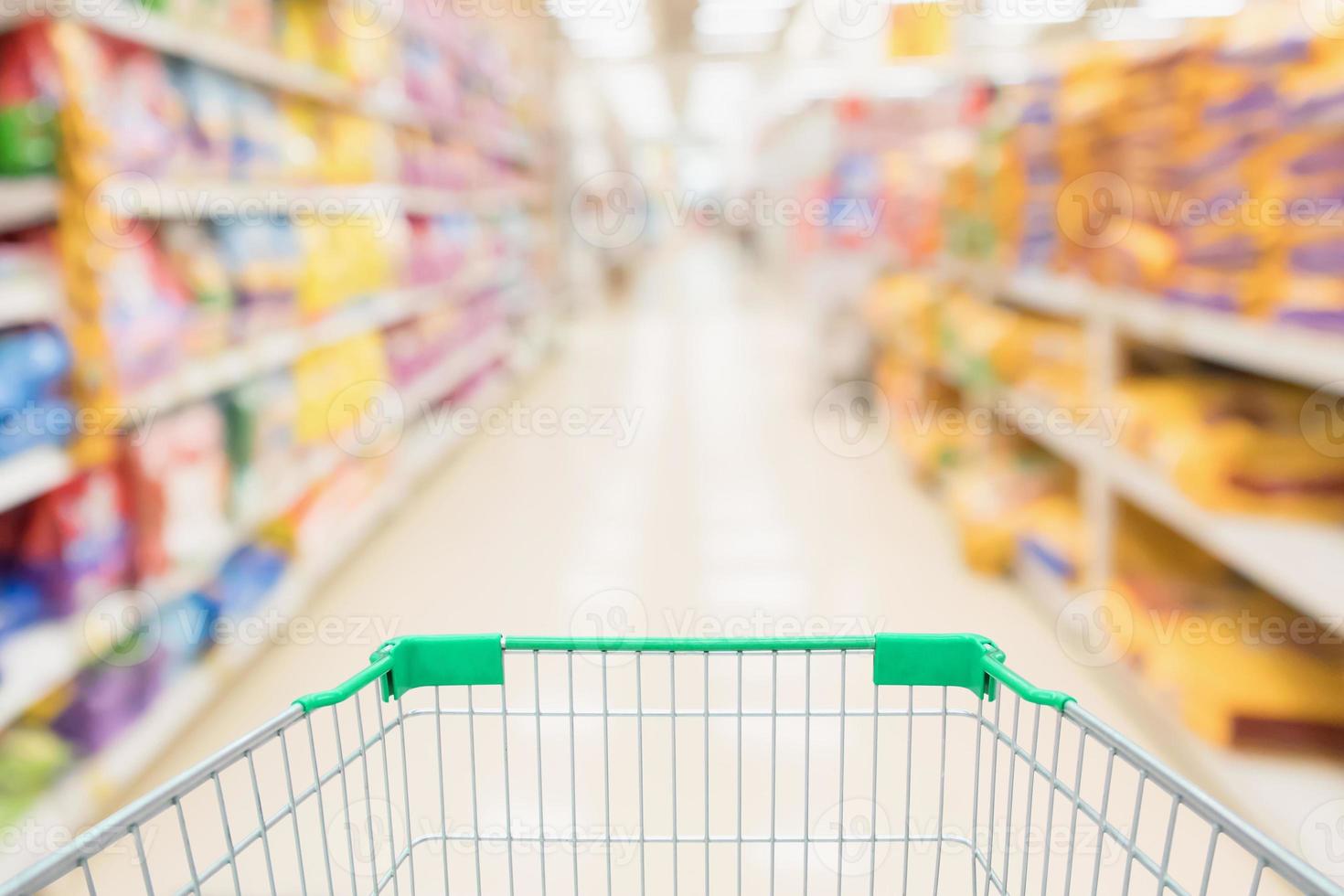 Einkaufswagen mit abstraktem Unschärfe-Supermarkt-Discounter-Gang und Tiernahrungsproduktregalen im Inneren mit defokussiertem Hintergrund foto