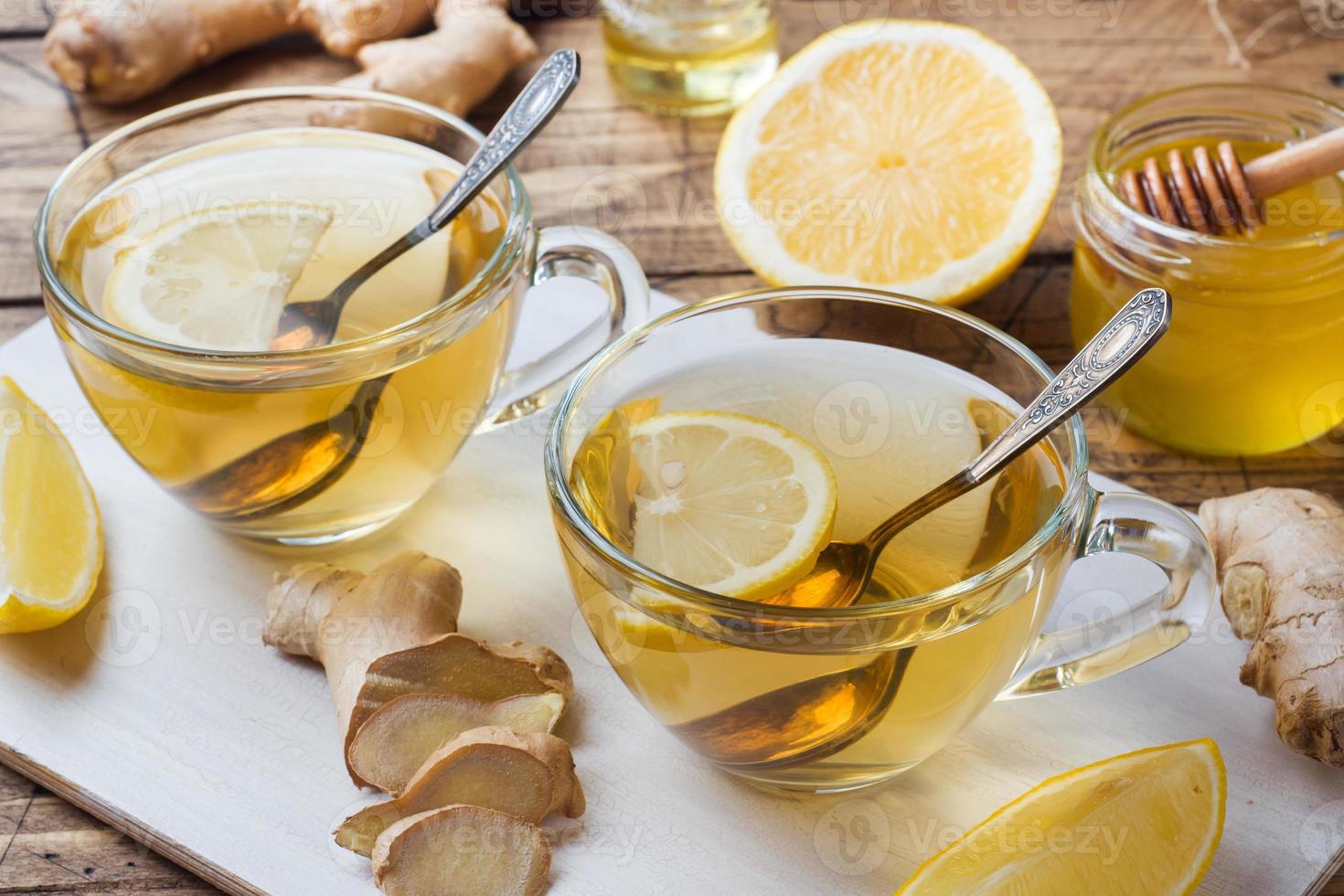 Zwei Tassen natürlicher Kräutertee, Ingwer, Zitrone und Honig auf Holzhintergrund. foto