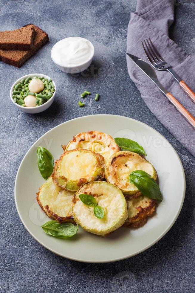 Scheiben gebratener Zucchini im Teig mit Knoblauch und Basilikum auf einem Teller. foto