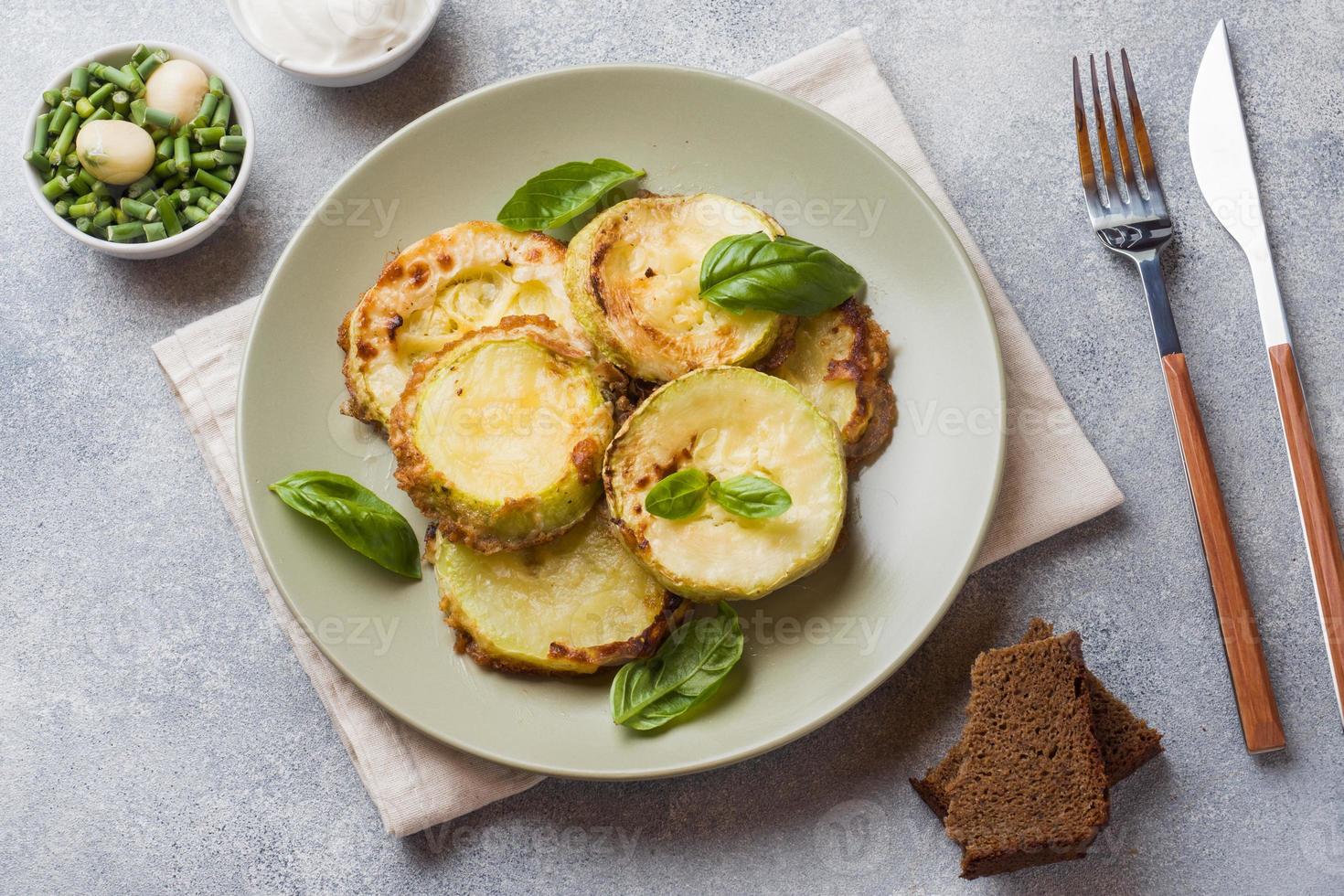 Scheiben gebratener Zucchini im Teig mit Knoblauch und Basilikum auf einem Teller. foto