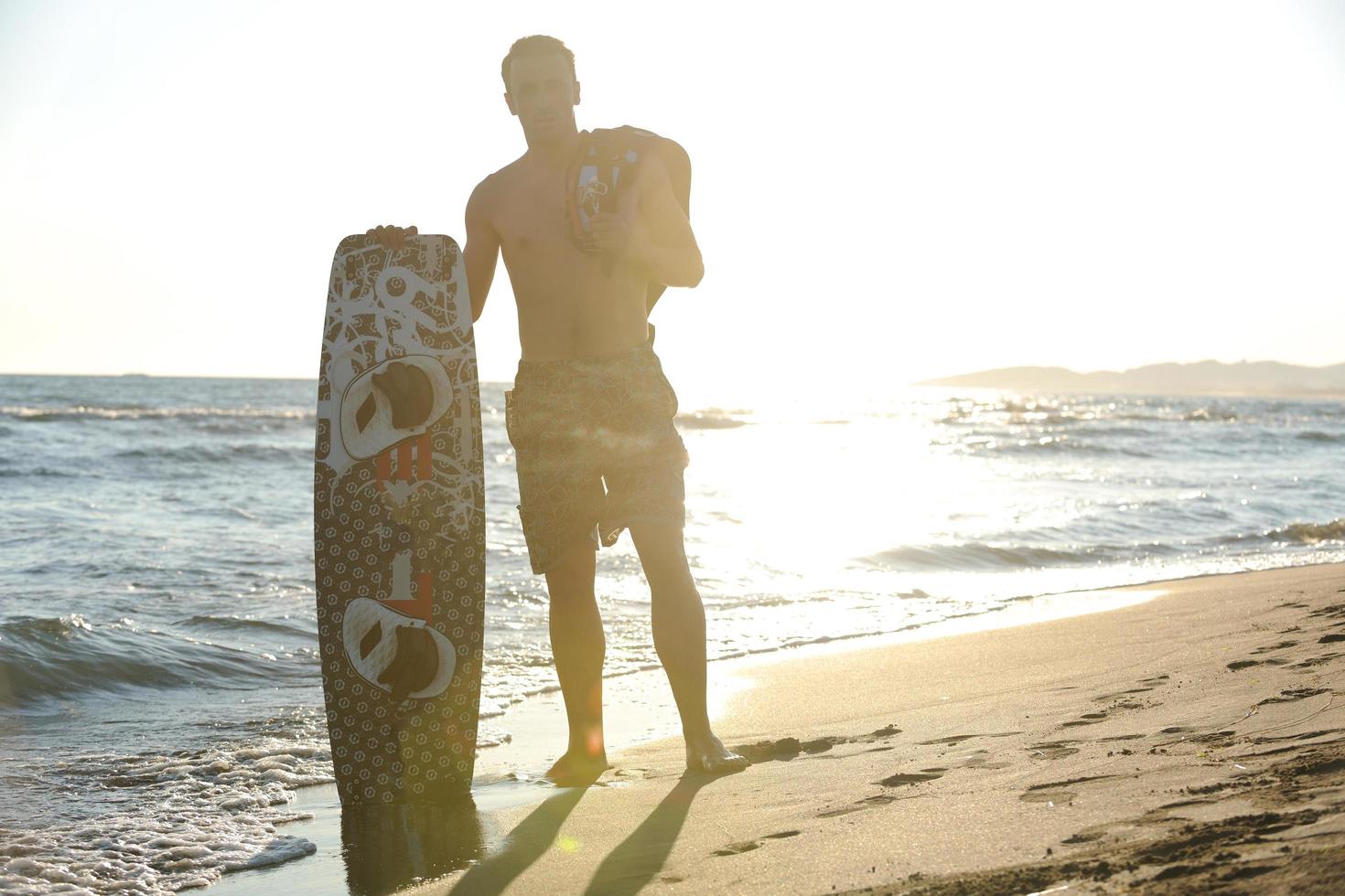 Porträt eines jungen Kitsurf-Mannes am Strand bei Sonnenuntergang foto