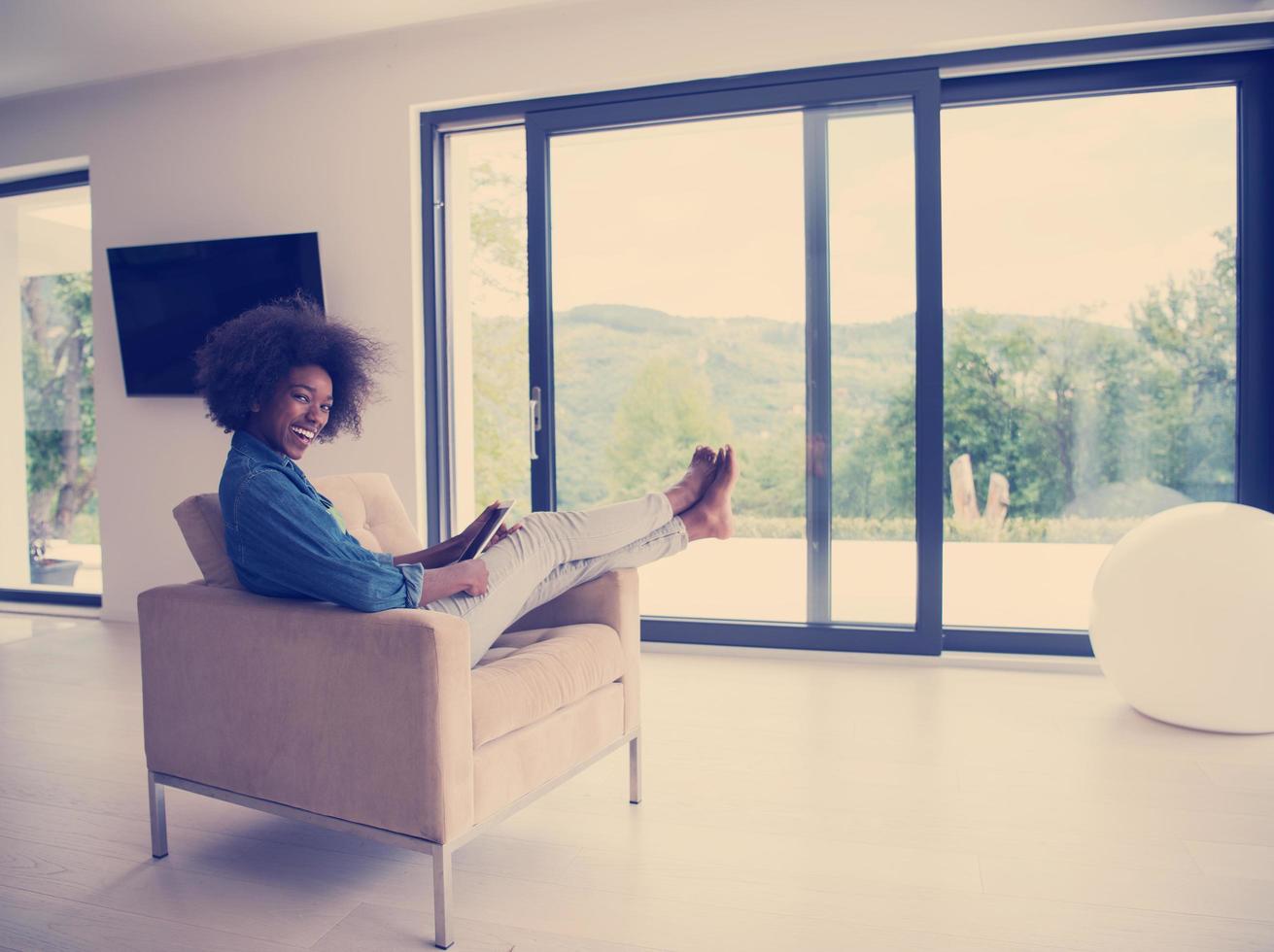 Afroamerikanerin zu Hause mit digitalem Tablet foto