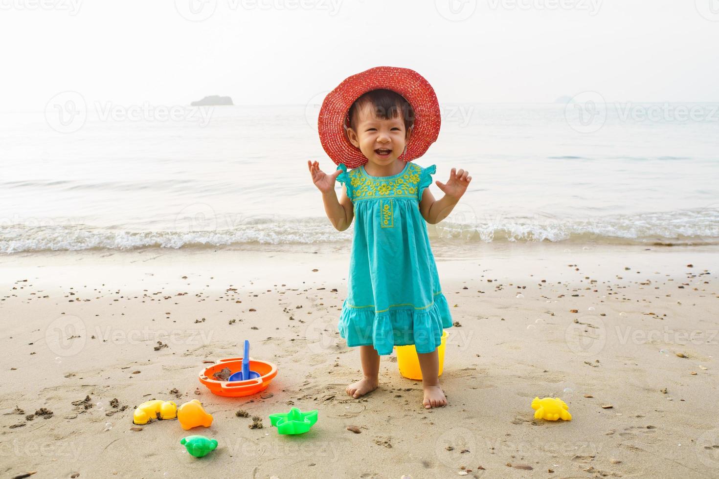 glückliches kleines kind, entzückendes blondes kleinkindmädchen, das am strand mit spielzeug spielt foto