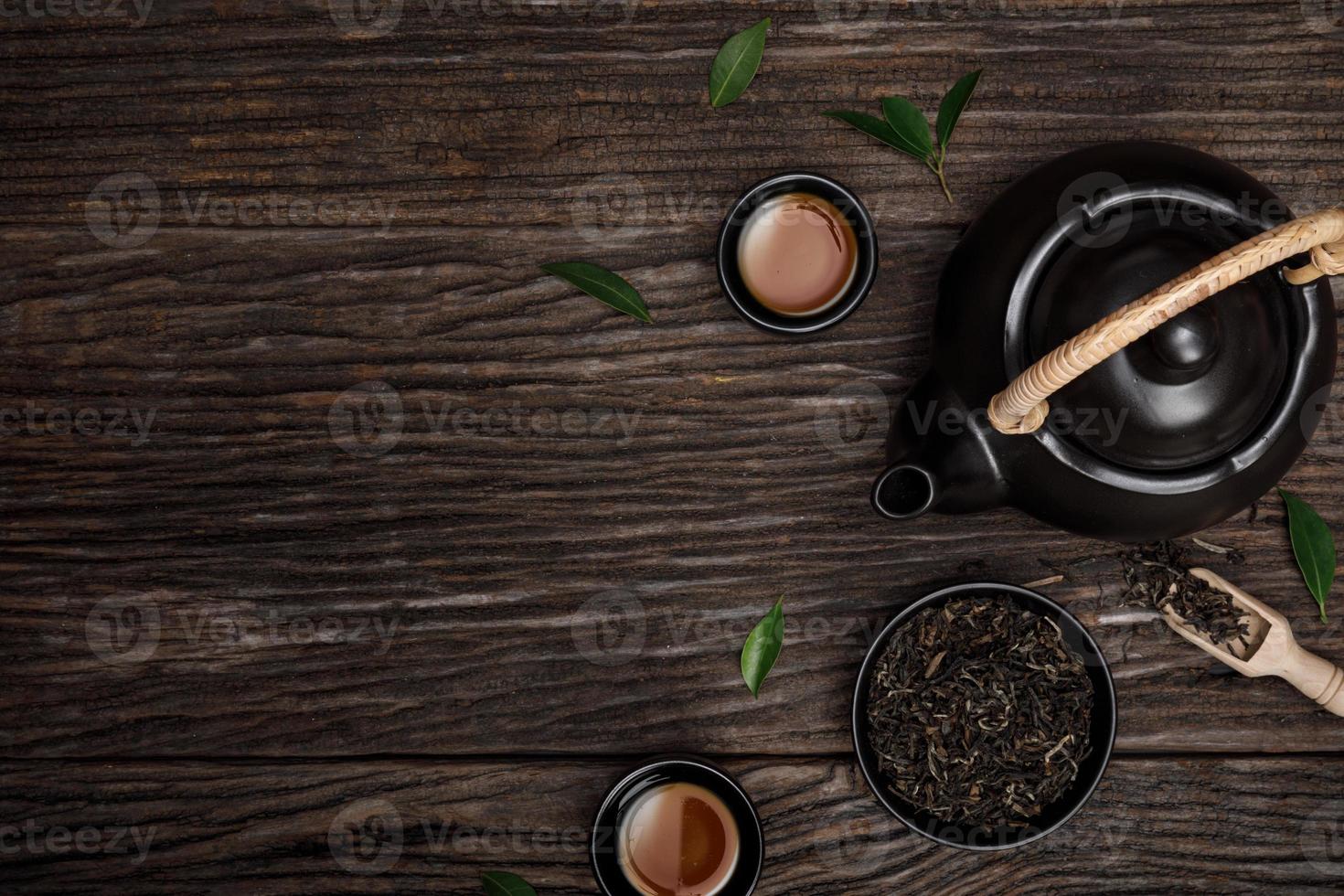 teetasse mit teekanne, bio-grünteeblätter und getrocknete kräuter auf dem hölzernen schreibtisch leerer raum kreative flachlage, organisches produkt aus der natur für gesundes mit traditionellem stil foto