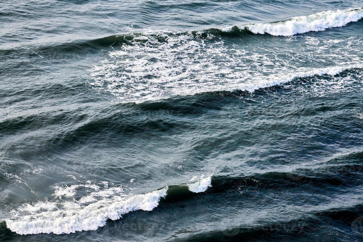 tiefblaues meerwasser, das mit schaumigen wellen spritzt, dunkelblaue gewellte ozeanwasseroberfläche, kopierraum foto