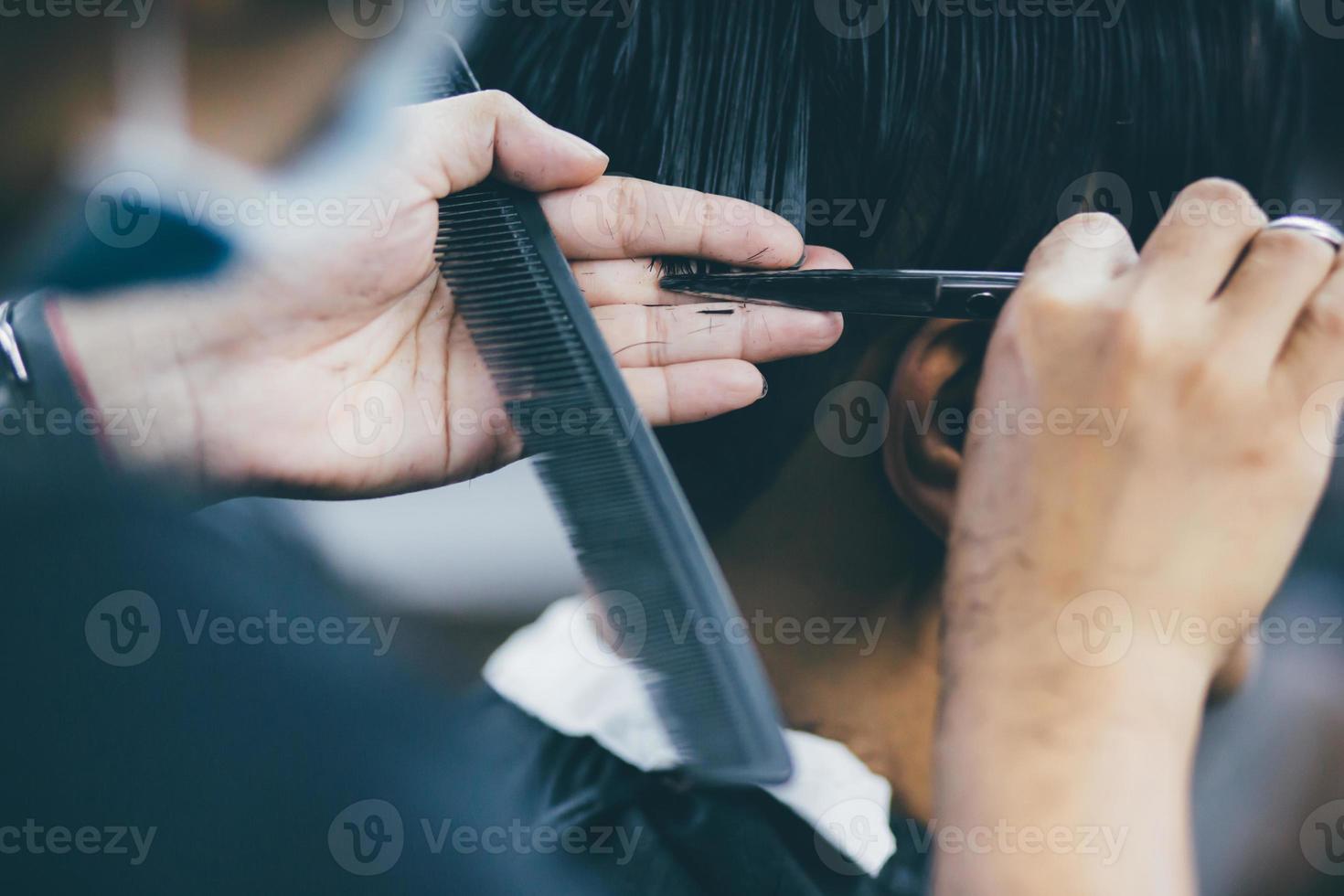 person mann haarschnitt bekommt stilvolle haare vintage rasur, mit haarschneider von friseur friseur mit händen im friseursalon. Füller-Vintage-Ton und selektiver Weichzeichner. foto
