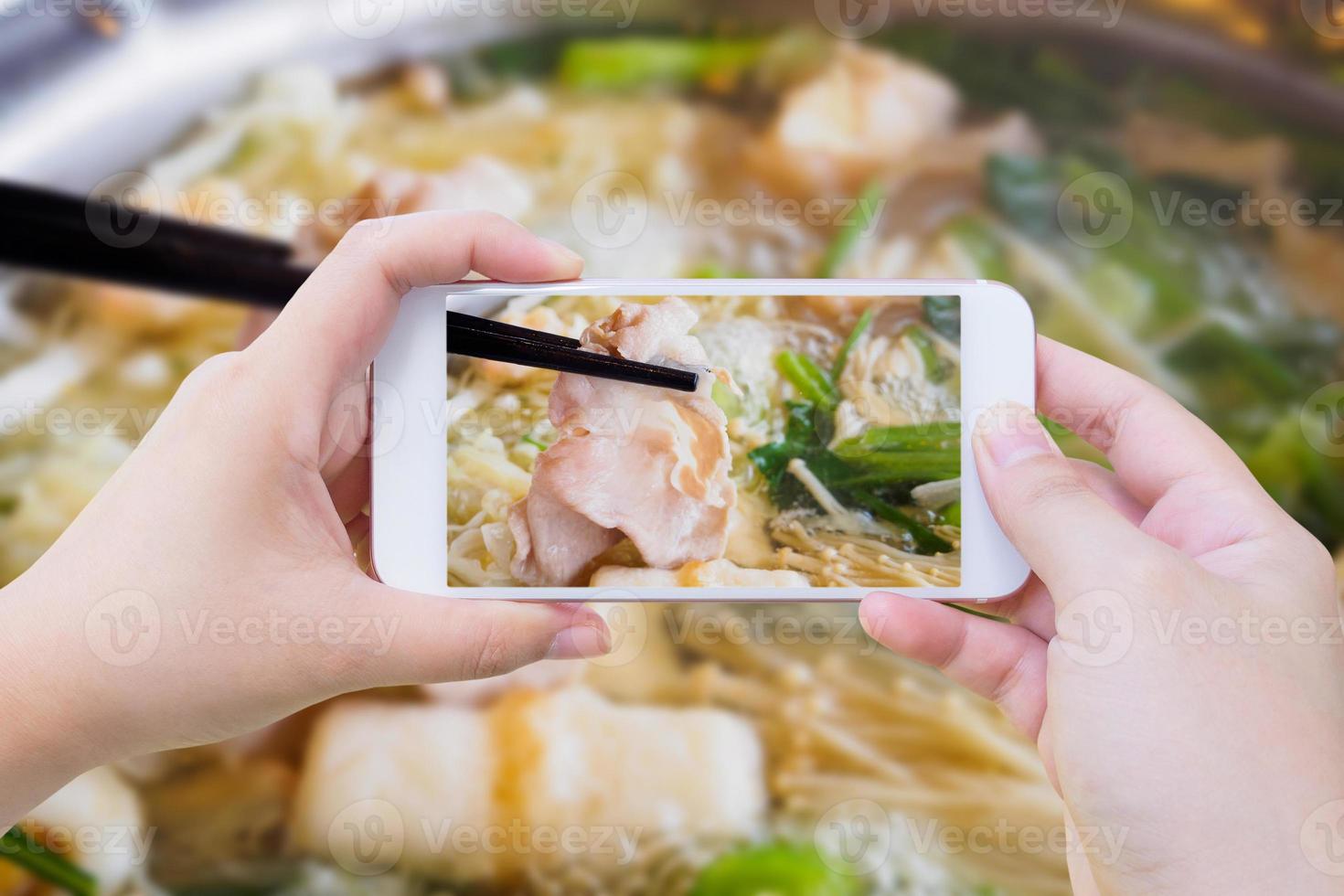 frau, die foto von sukiyaki shabu shabu macht