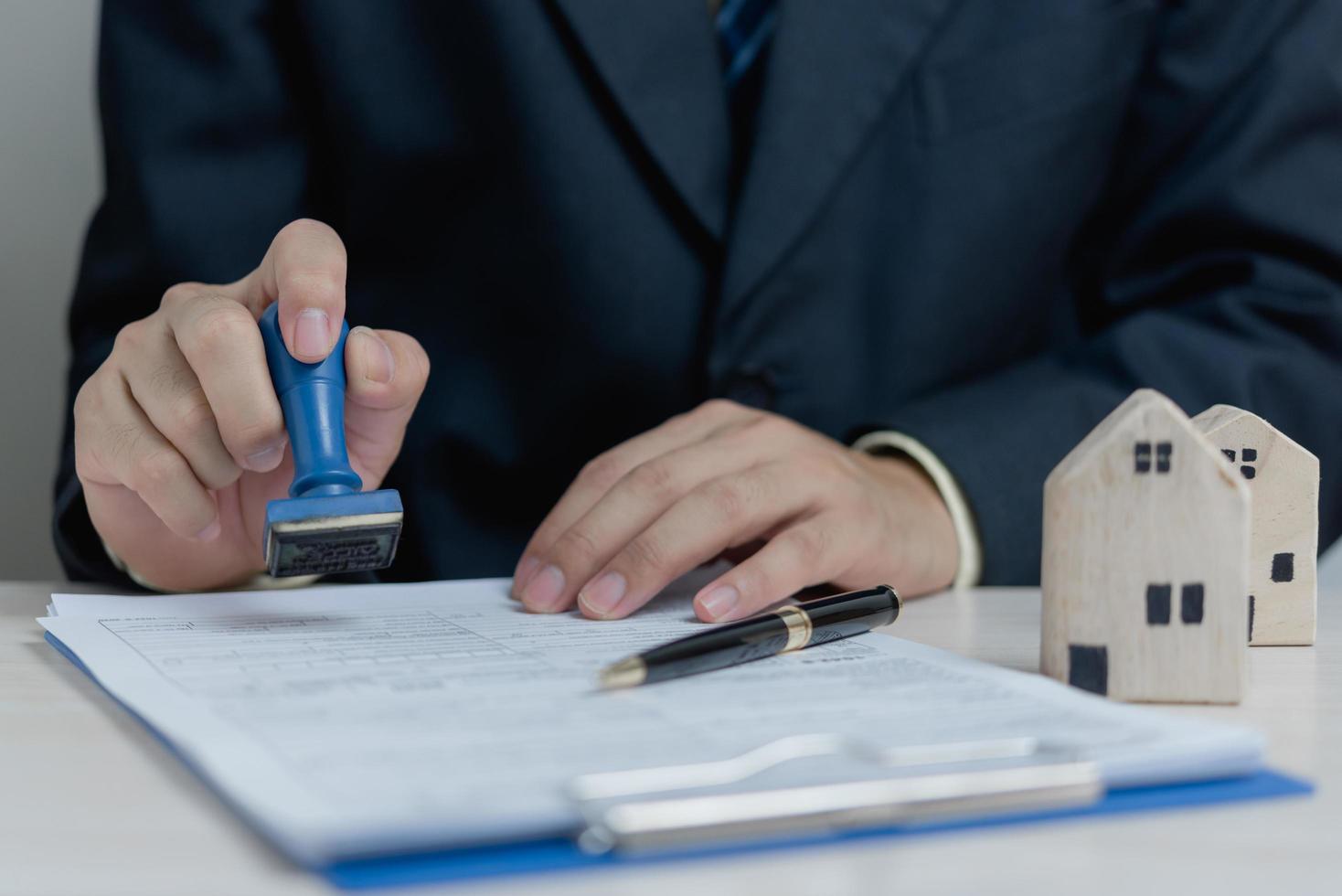 kauf und verkauf von immobilien oder kreditaufnahme, bankdarlehen, genehmigte investitionen. geschäftsmann-stempeldokument auf schreibtisch. foto