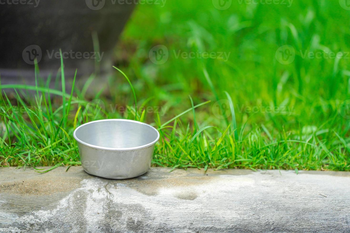 Zinkbecher auf dem Fußteil mit Gartenhintergrund. foto