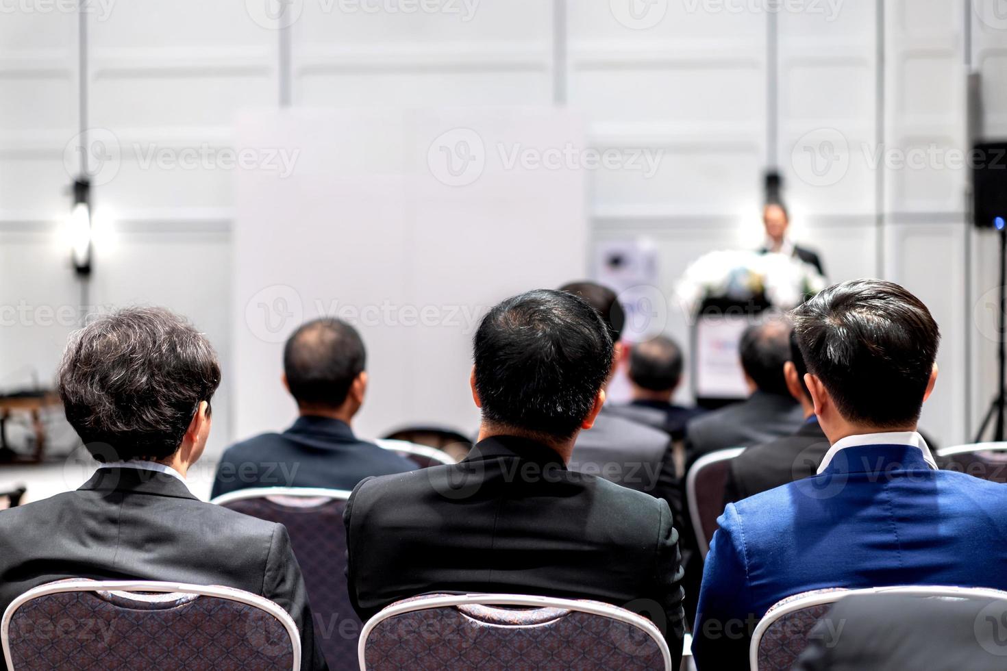 rückseite sitzen drei asiatische geschäftsleute und hören redner auf dem podium vor dem konferenzraum. foto