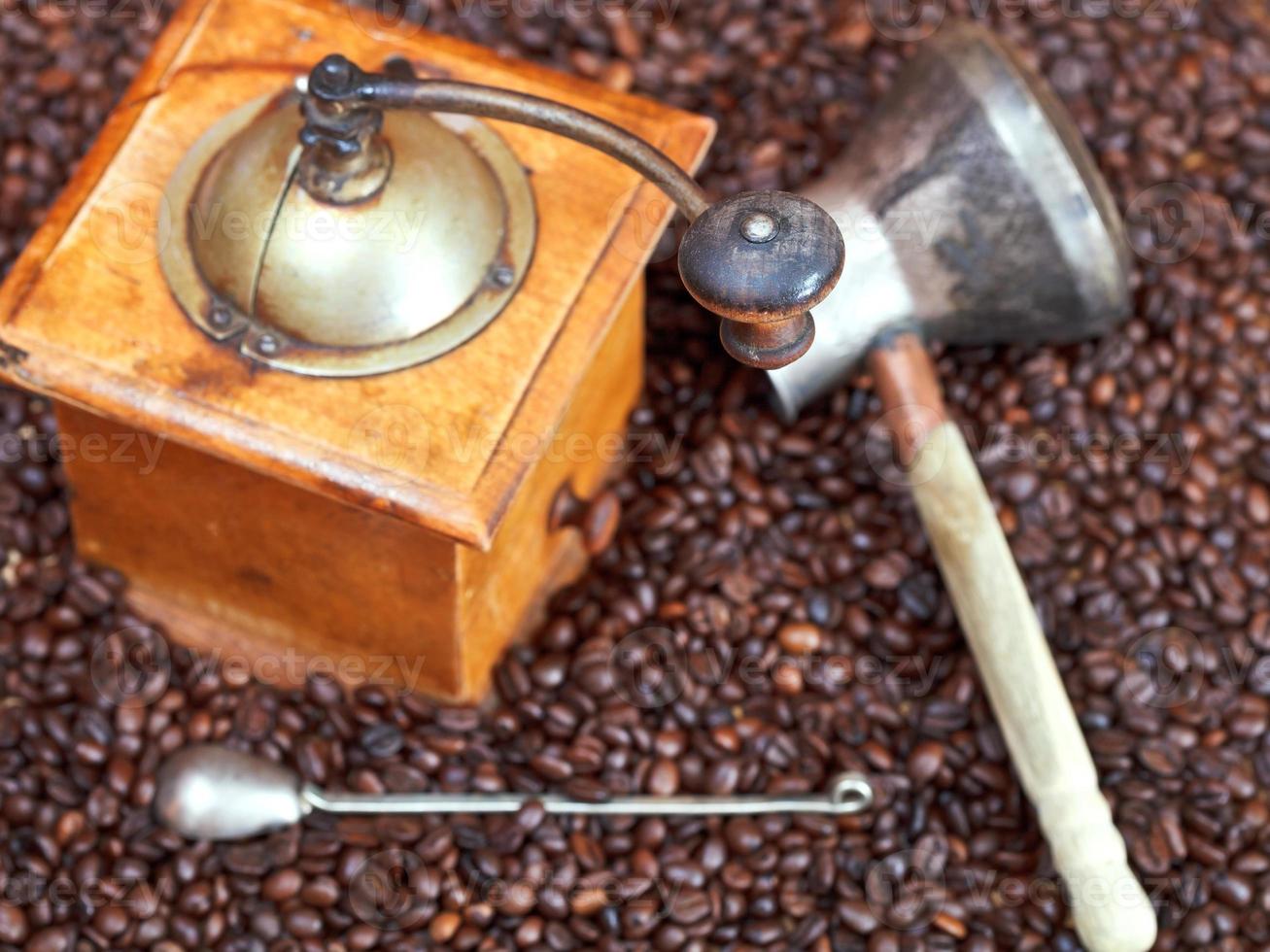 Kaffeemühle und Kupfertopf auf gerösteten Bohnen foto