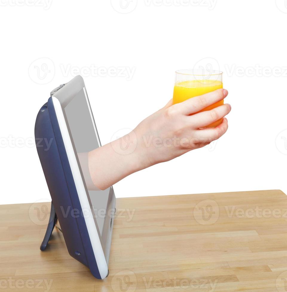 Glas mit frischem Orangensaft in der Hand lehnt sich aus dem Fernseher foto