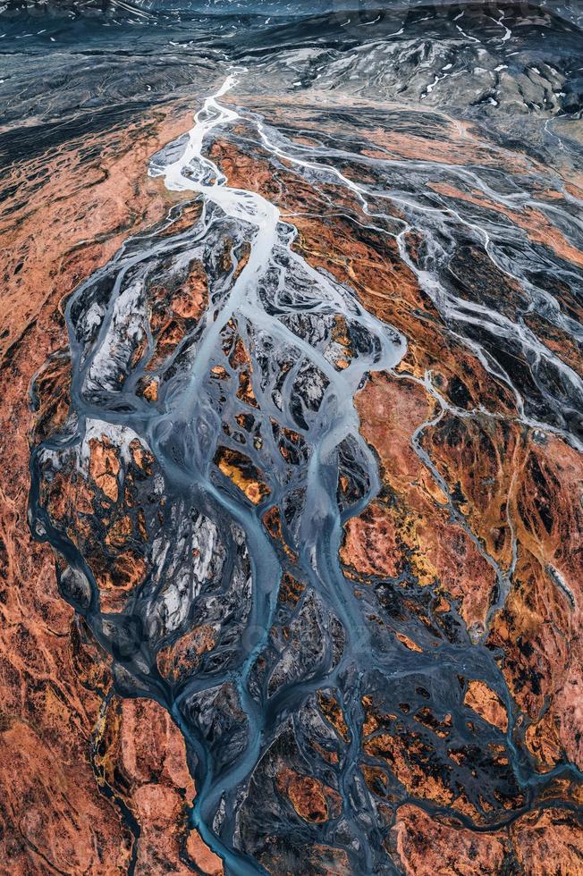 abstraktes Gletscherflussmuster, das im Sommer durch vulkanische Lavafelder im isländischen Hochland fließt foto