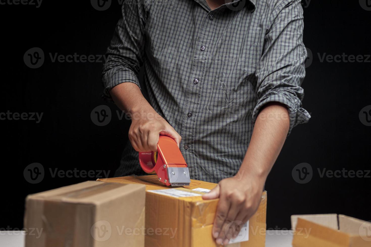 Ein Mann packt in seinem Zimmer zu Hause eine kleine Schachtel seines Online-Geschäfts. foto