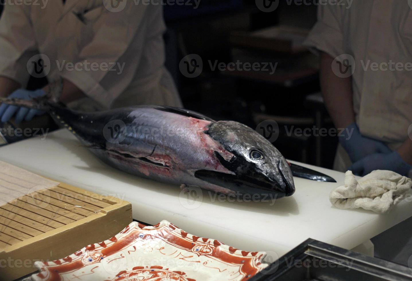 Sushi-Meister, der fachmännisch einen Thunfisch schneidet foto