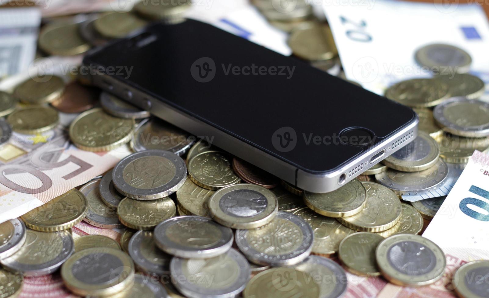 mobiles bezahlen und smartphone - ein mobiles gerät, das auf einem geldhaufen liegt foto