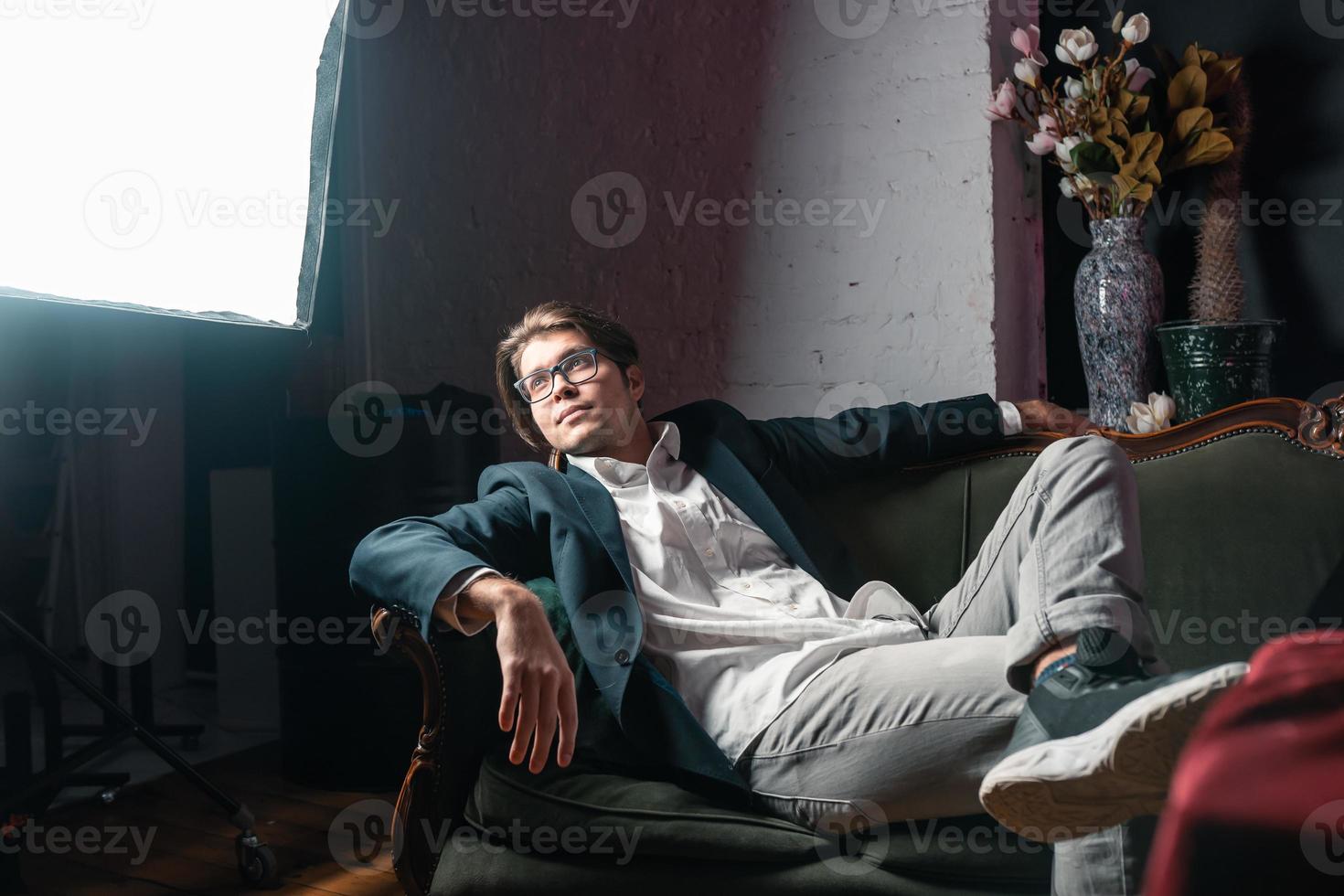 Nahaufnahmeporträt eines attraktiven jungen Mannes, der auf der Couch sich entspannt foto