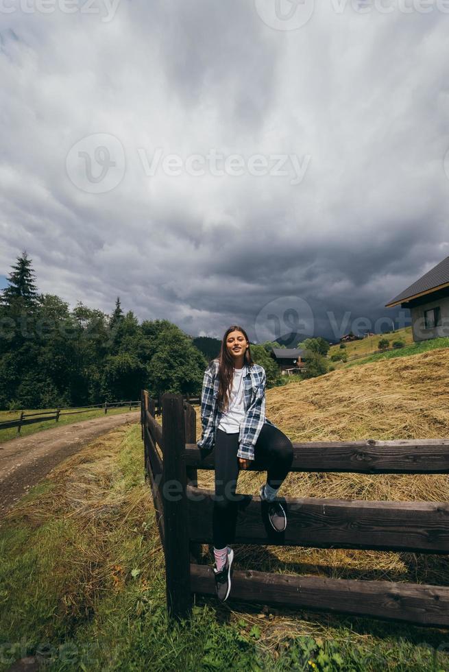 eine junge attraktive kaukasische frau, die auf einem zaun sitzt foto