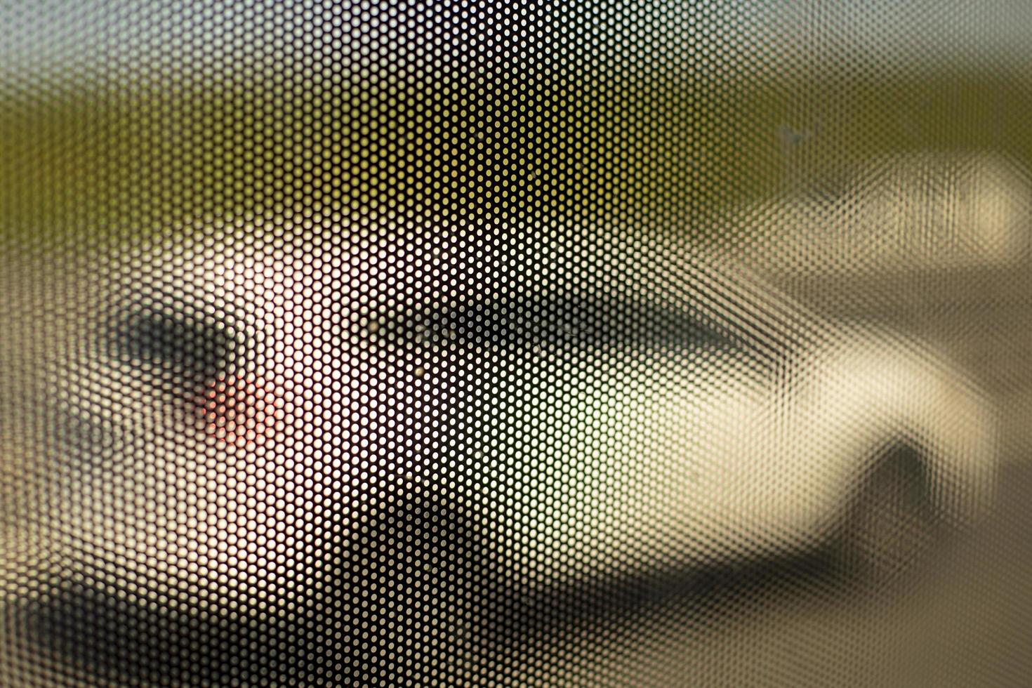 Maschenstruktur auf Glas des Busses. Oberflächendetails von kleinen Löchern. verschwommener Hintergrund durch kleine Löcher geschossen. foto