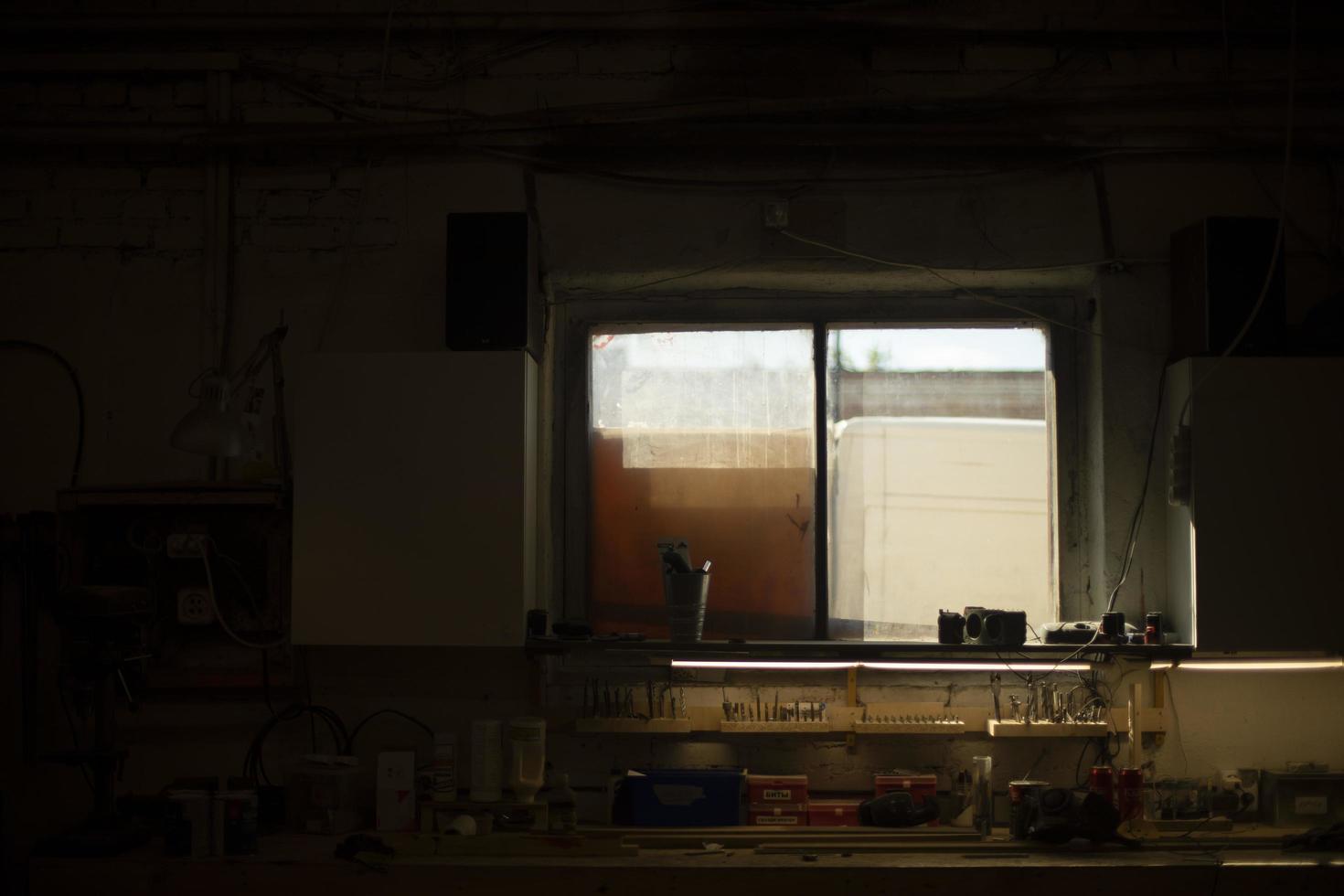 Fenster im Zimmer. Details des Innenraums der Werkstatt. Licht vom Fenster im dunklen Raum. foto