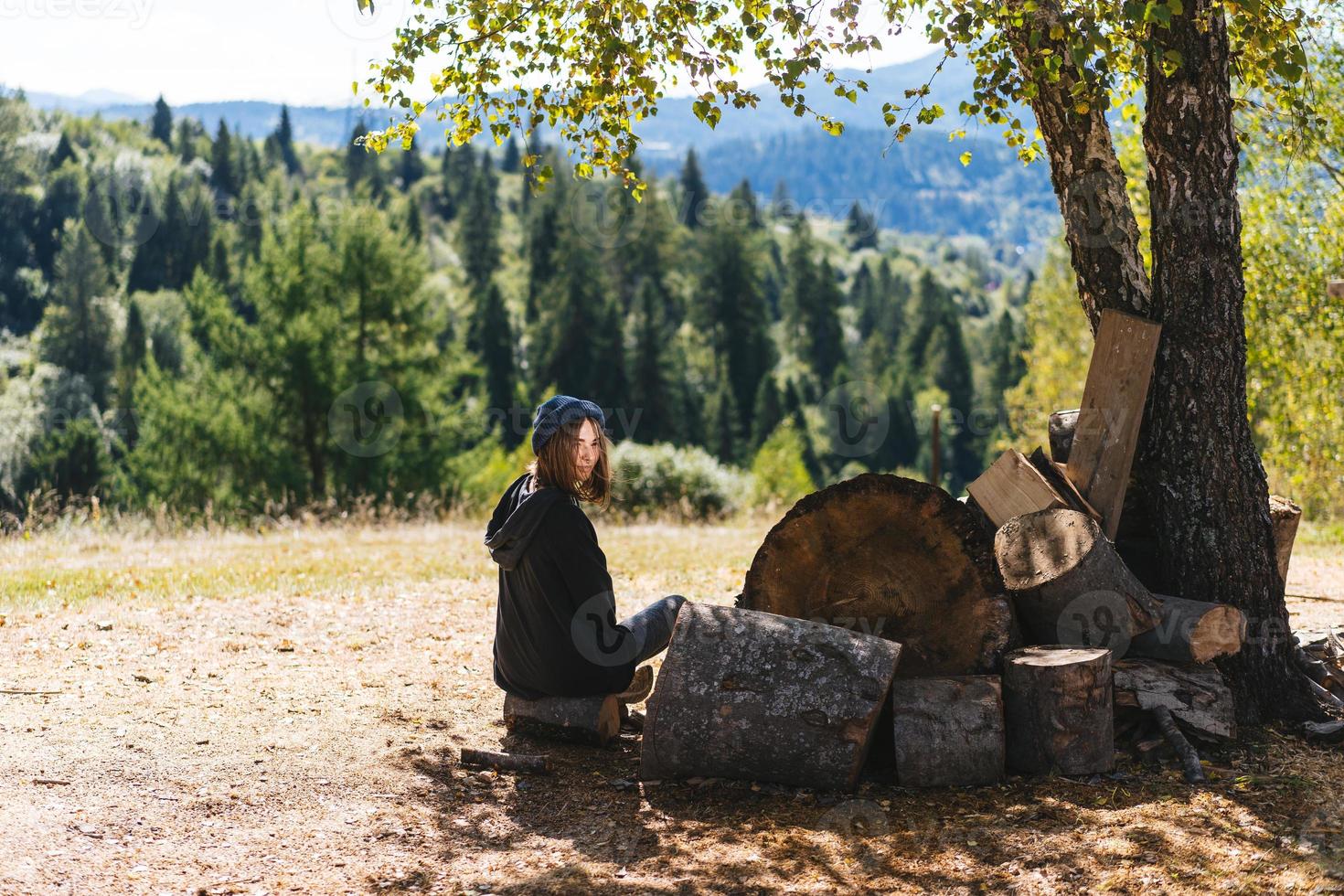 Frau neben Baumstämmen aus geschnittenem Holz foto