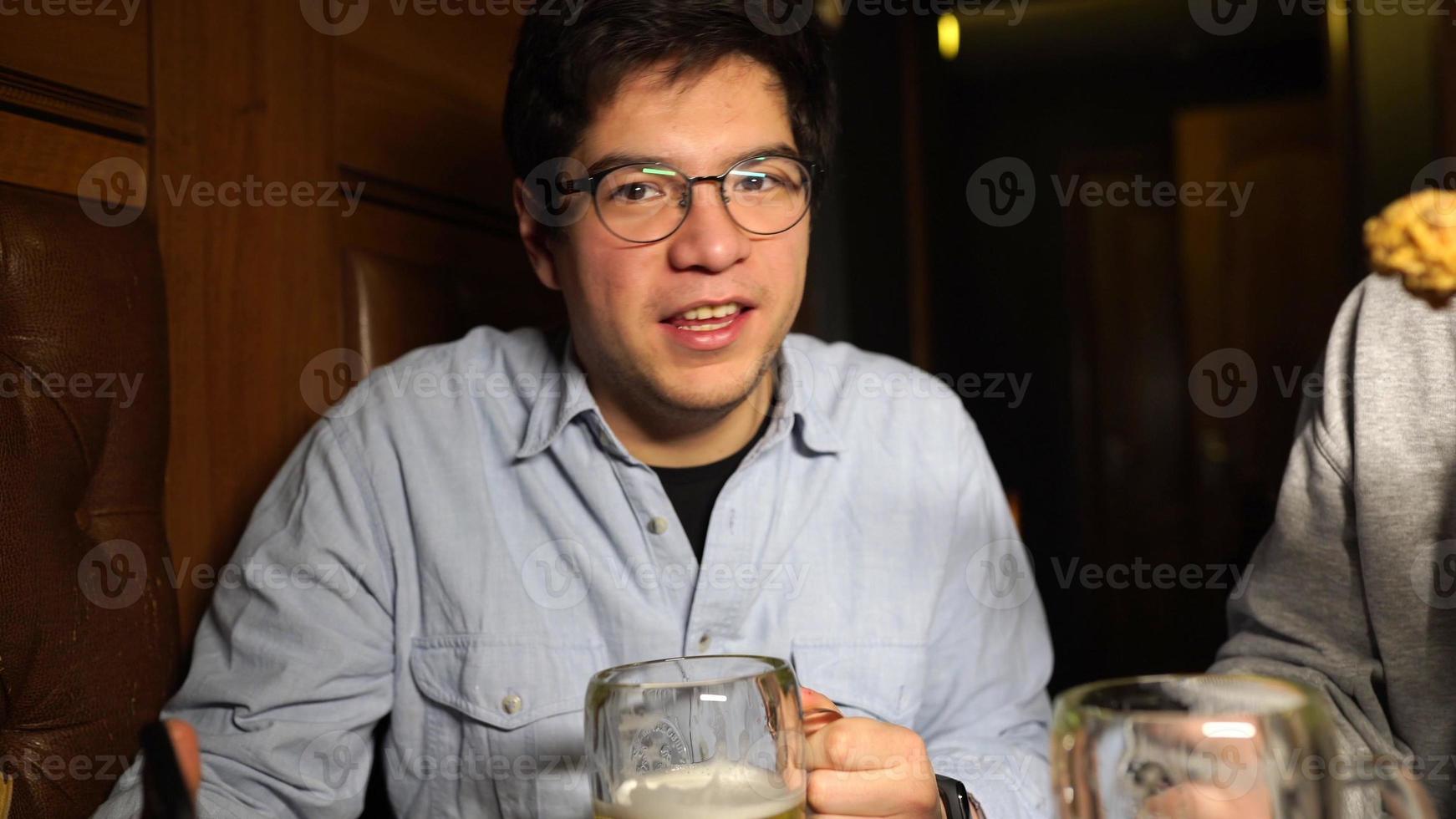 Typ mit einem Bier in einer Bar mit Freunden an einem Samstagabend foto