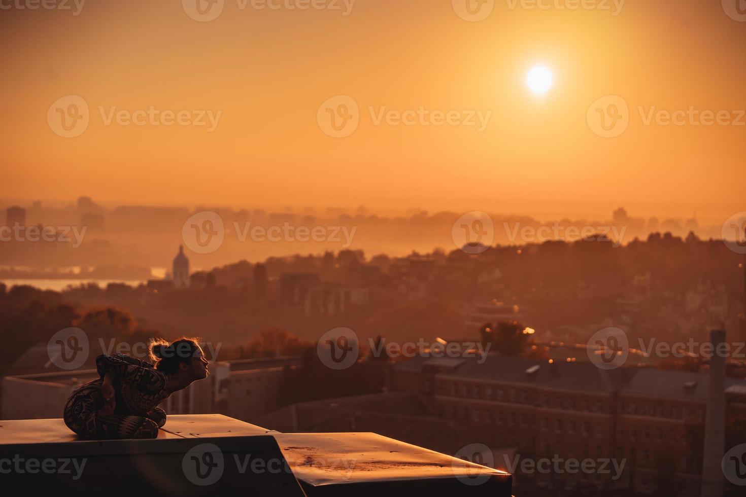 Frau beim Yoga auf dem Dach eines Wolkenkratzers in der Großstadt. foto