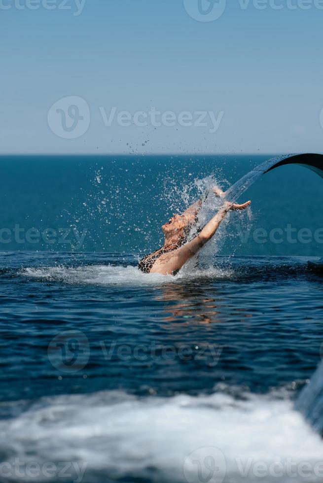 junge frau, die unter schwimmbadwasserfallstrahl sich entspannt foto