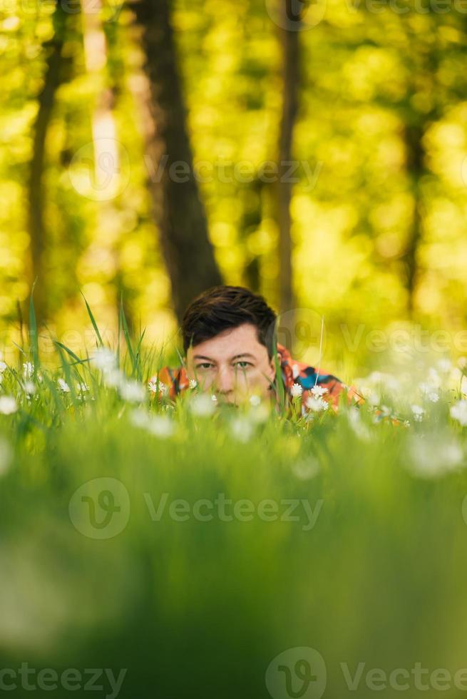 junger Mann versteckt sich im grünen Gras foto