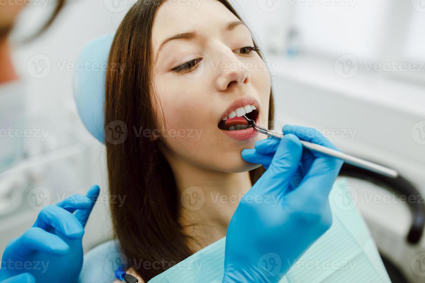 Inspektion der Zähne des Mädchens mit Hilfe eines Spiegels foto