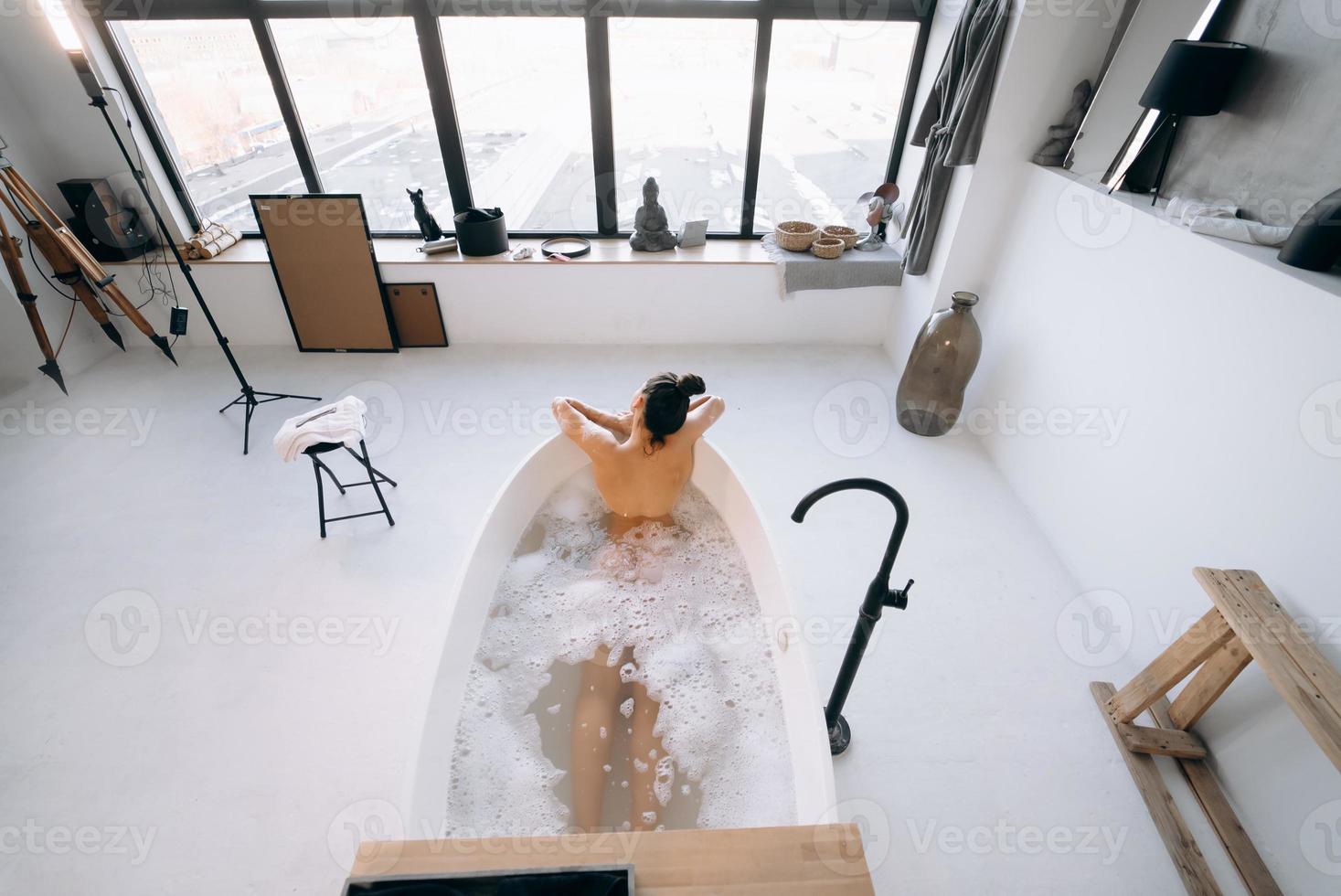 entspannte dame, die badet, genießt und entspannt, während sie in der badewanne liegt, draufsicht foto