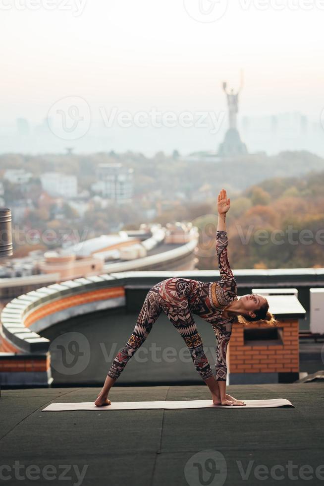 Frau beim Yoga auf dem Dach eines Wolkenkratzers in der Großstadt. foto