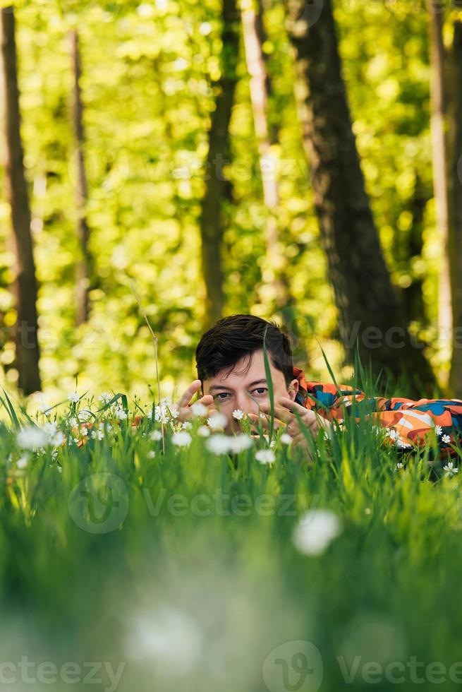 junger Mann versteckt sich im grünen Gras foto