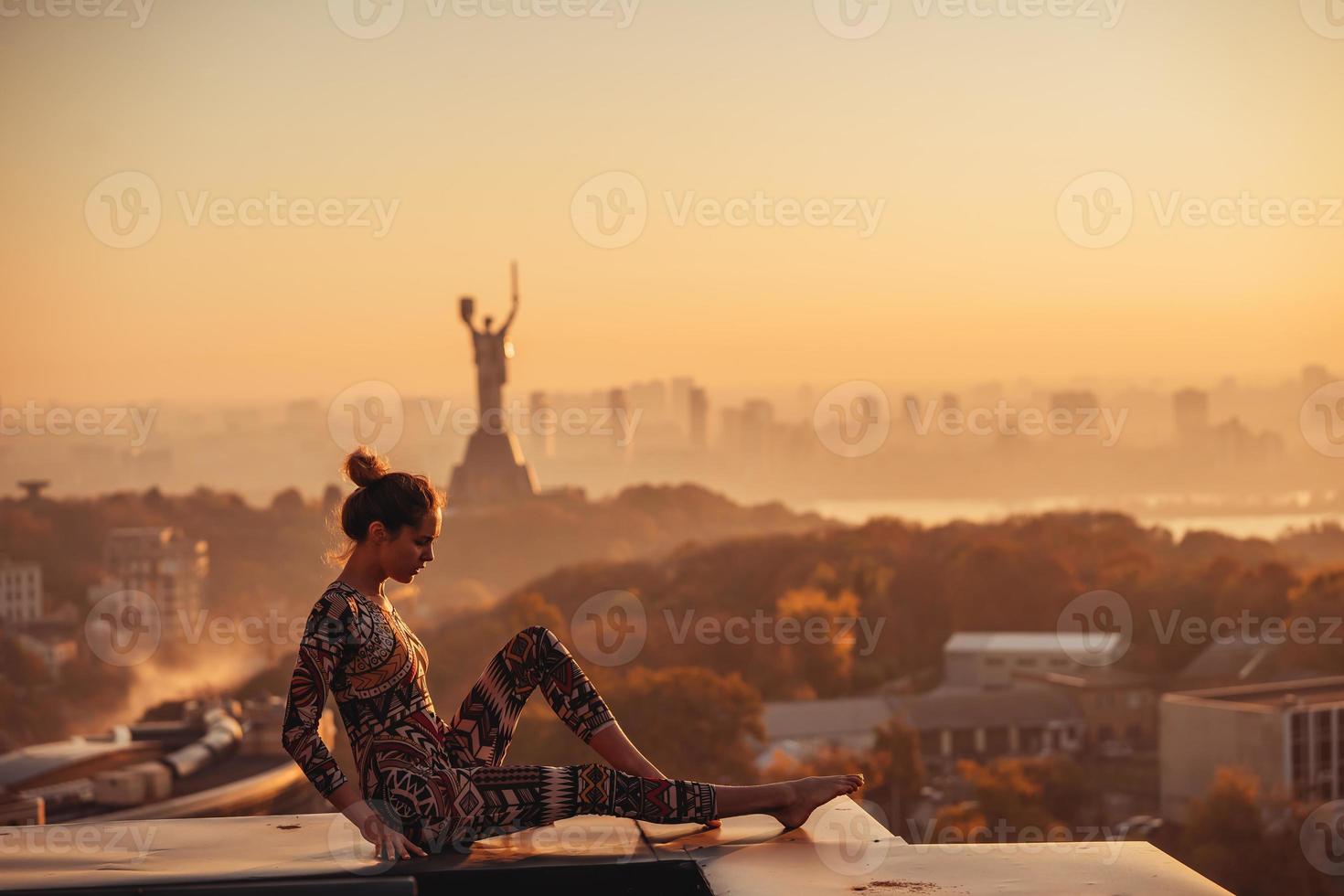 Frau beim Yoga auf dem Dach eines Wolkenkratzers in der Großstadt. foto