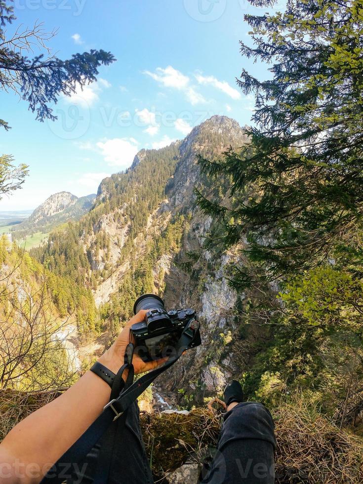 ein fotograf beobachtet mit seiner kamera in der hand von einem berggipfel aus. foto