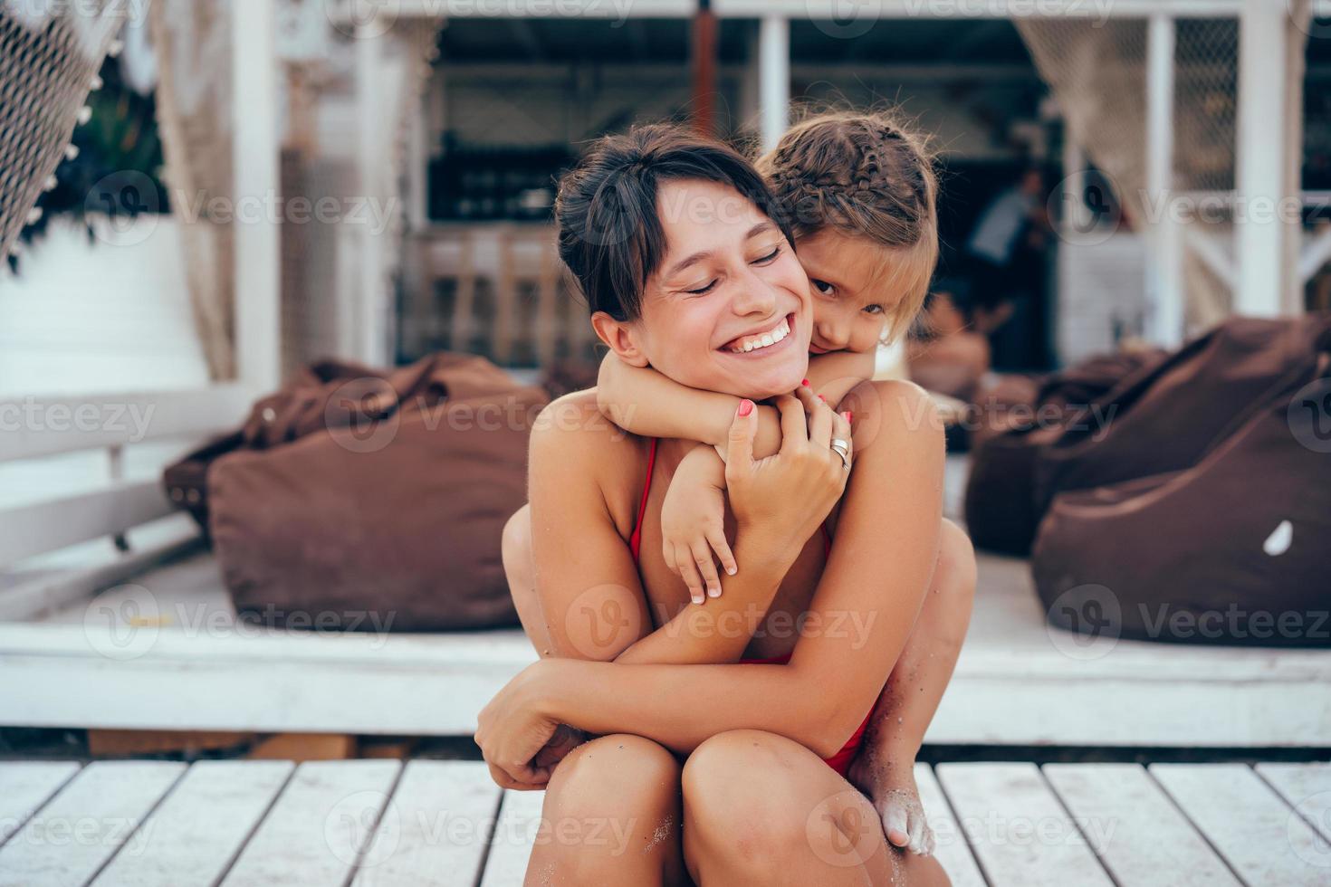 junge Mutter, die Tochter Huckepack am Strand gibt foto