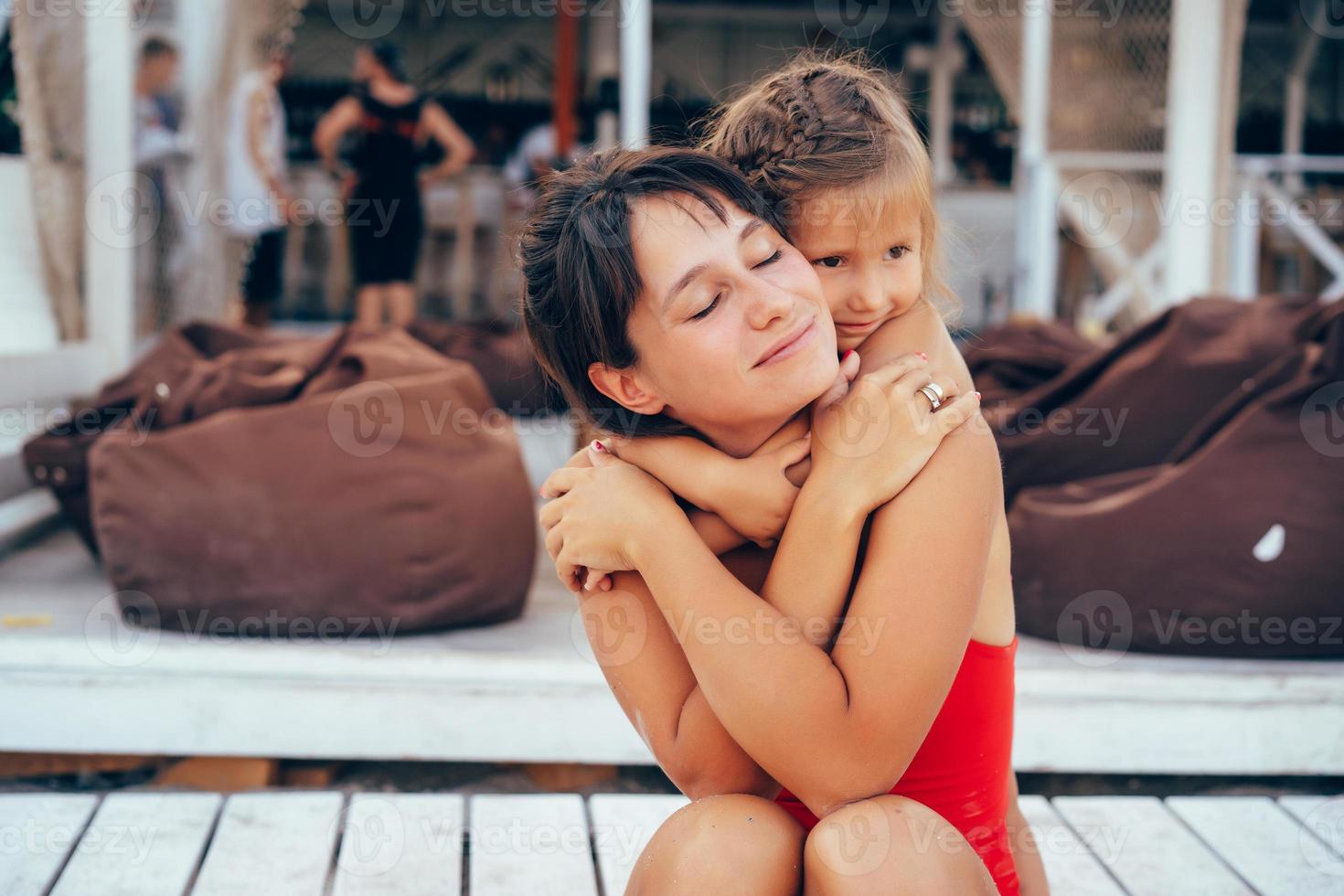 junge Mutter, die Tochter Huckepack am Strand gibt foto
