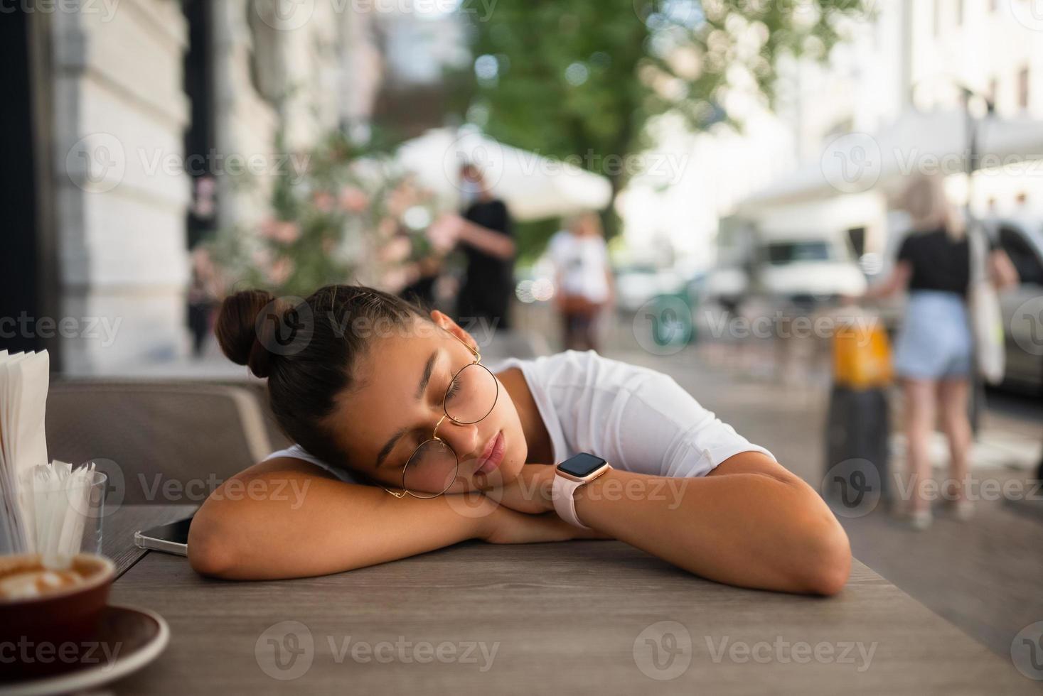 gelangweiltes, gleichgültiges Mädchen an einem Tisch in einem Straßencafé foto