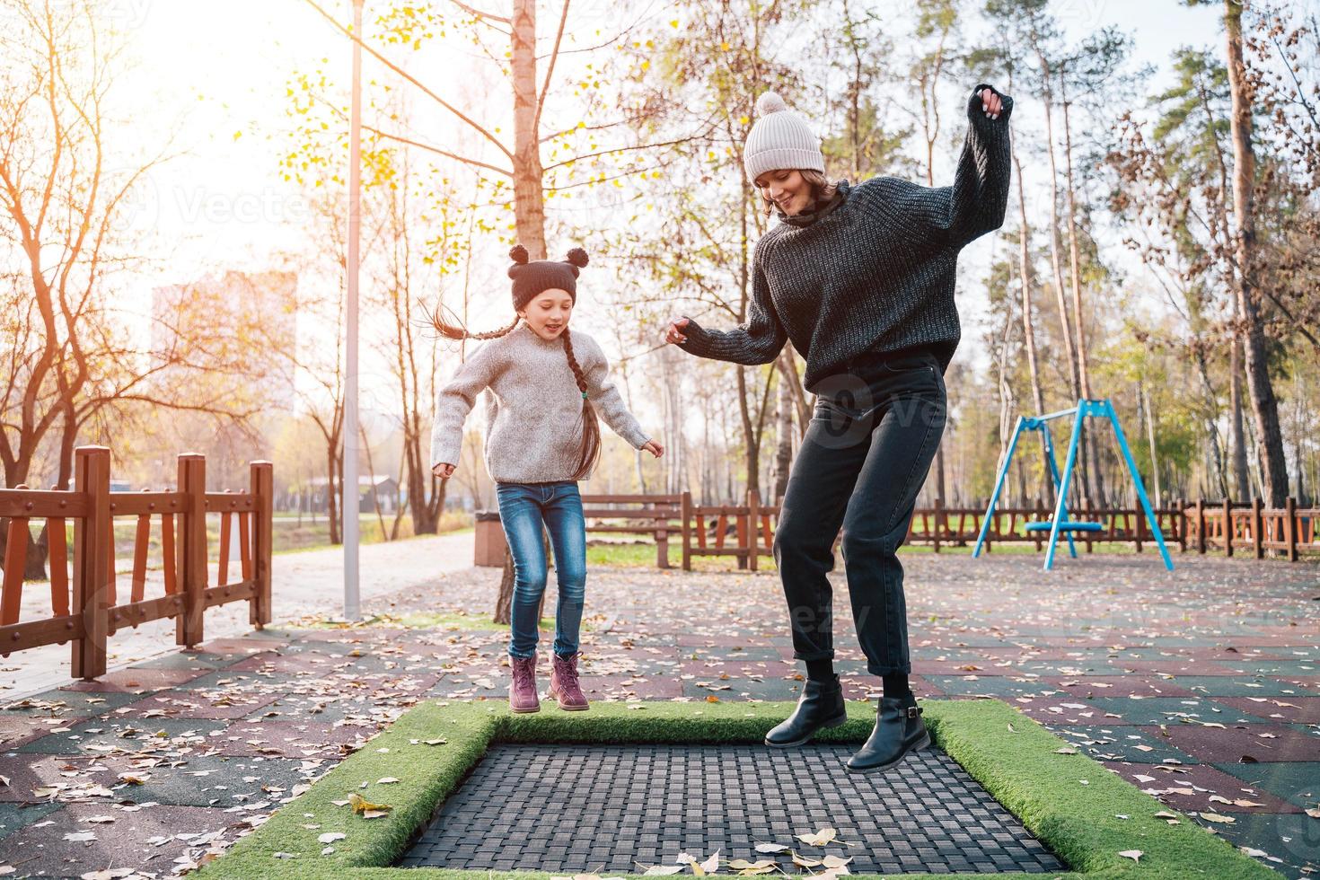 mutter und ihre tochter springen zusammen auf dem trampolin im herbstpark foto