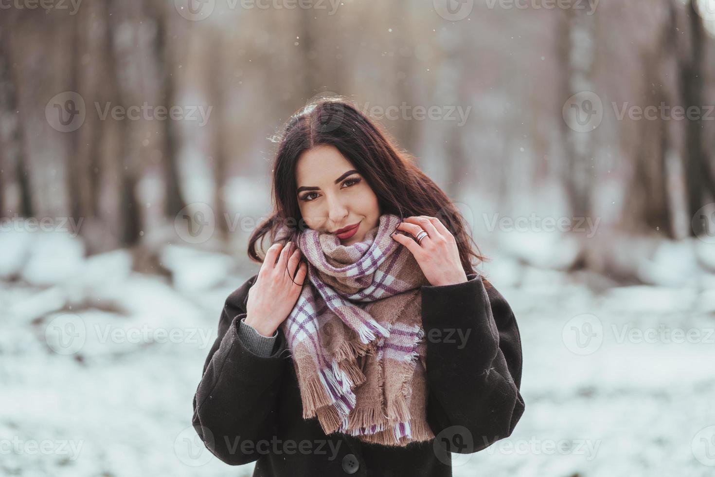 junges schönes Modell, das im Winterwald aufwirft. stilvolles Modeporträt foto