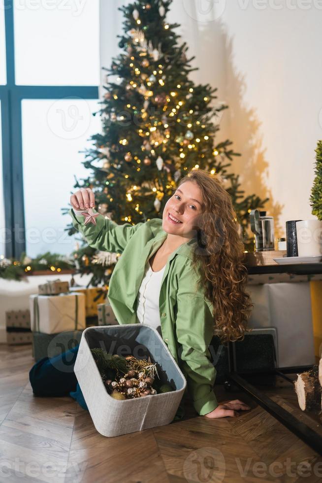 junge frau nimmt spielzeug für den weihnachtsbaum aus der schachtel foto