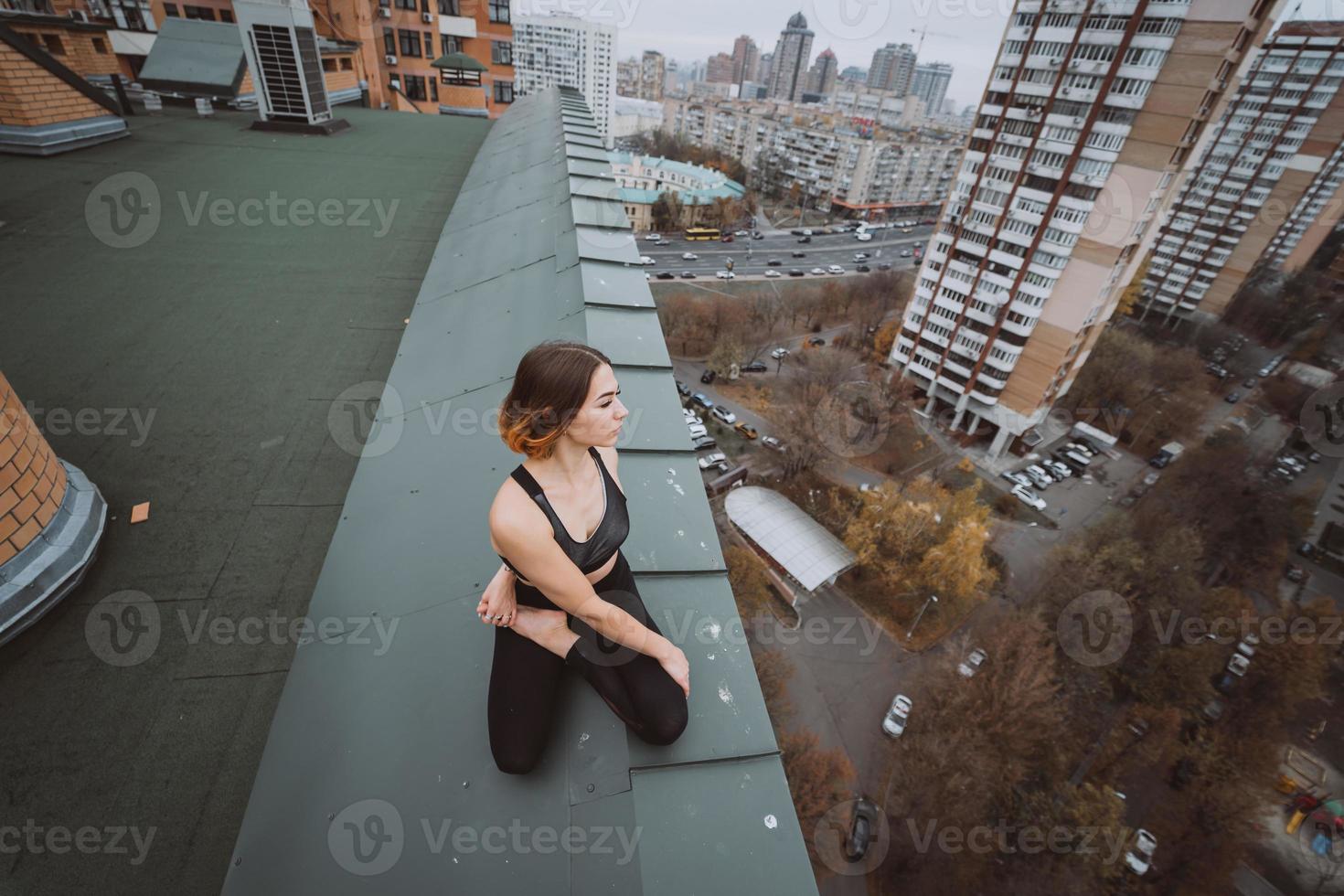 Frau, die Yoga auf dem Dach praktiziert und Yoga-Übungen macht foto