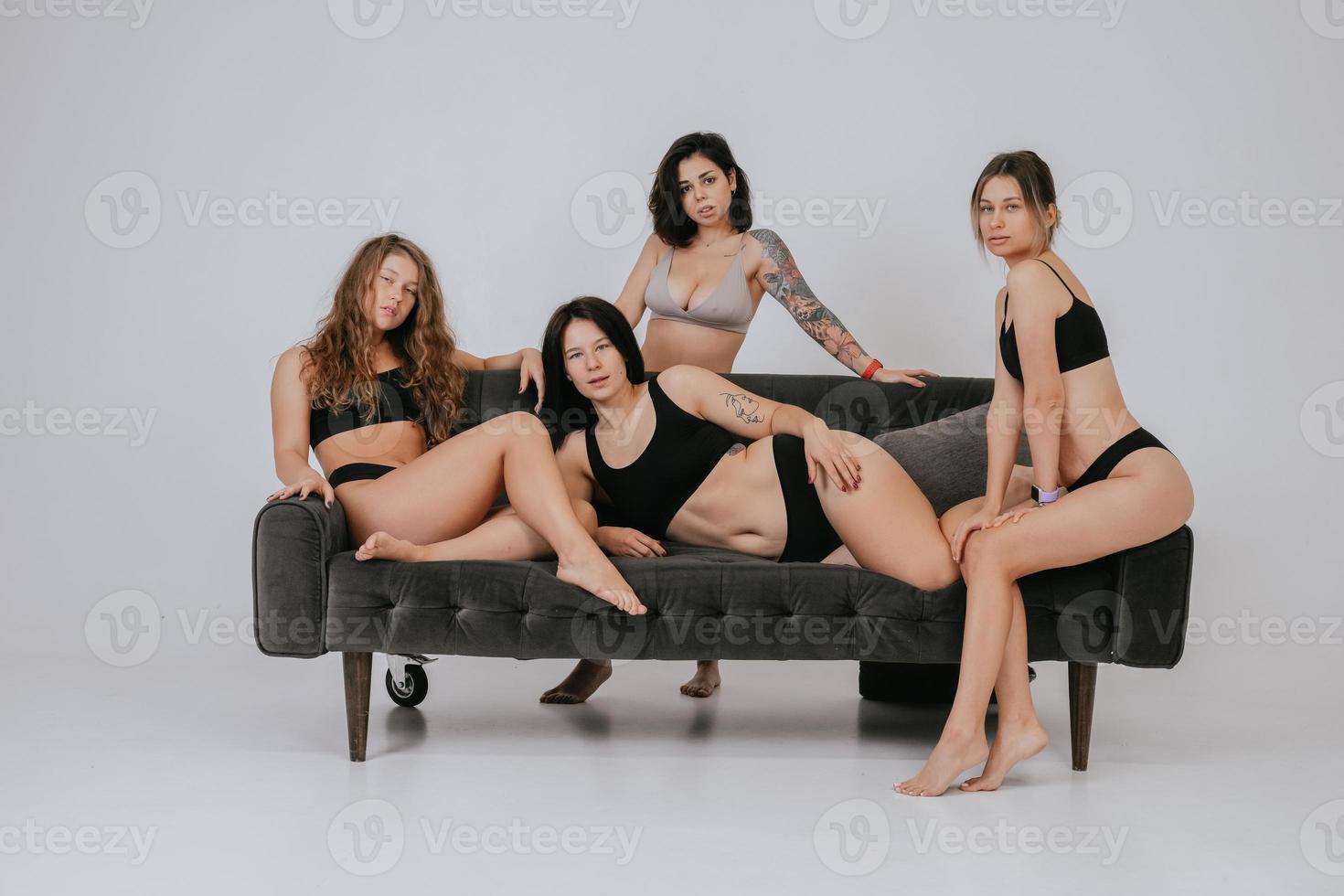 Diverse Models in bequemer Unterwäsche posieren auf einem großen Sofa foto