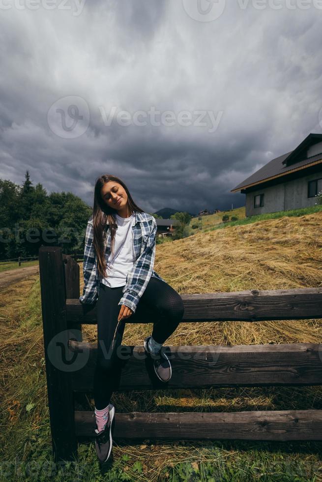 eine junge attraktive kaukasische frau, die auf einem zaun sitzt foto