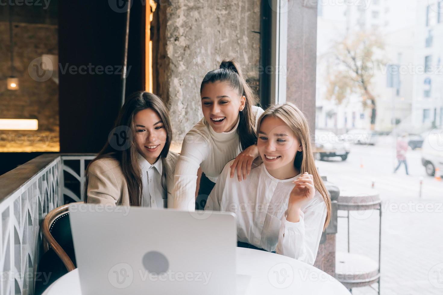 Eine Gruppe von Freundinnen in einem Café schaut auf einen Laptop foto