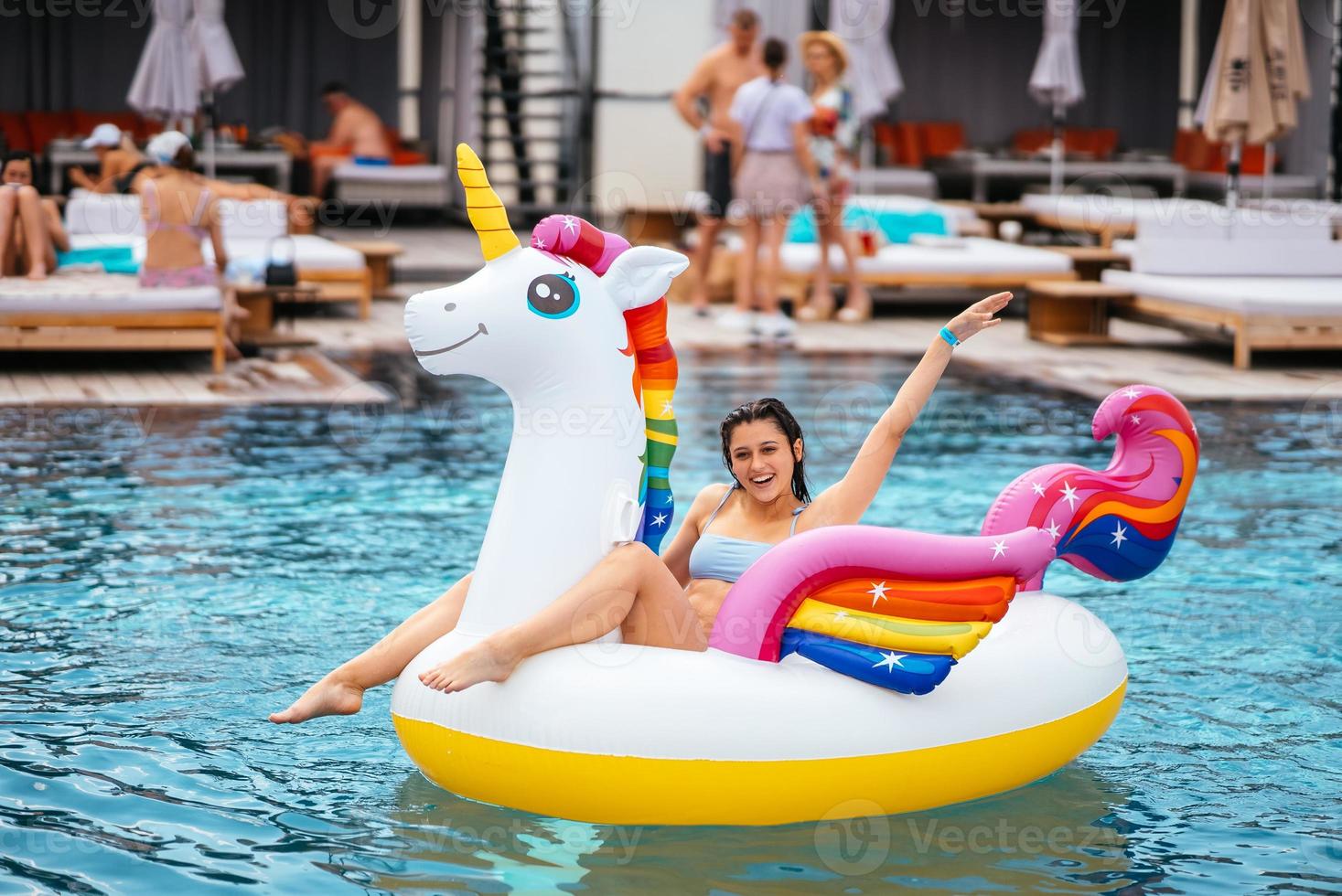 Frau auf aufblasbarer Einhorn-Spielzeugmatratze schwimmt im Pool. foto